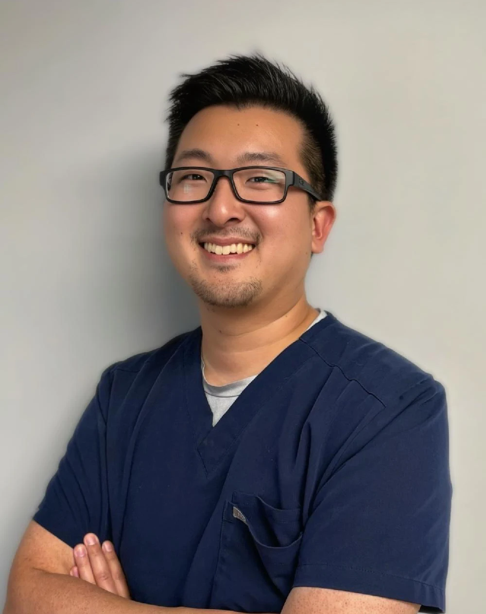 Isaac Kim Smiles Warmly with His Arms Crossed for the Main Page Header
