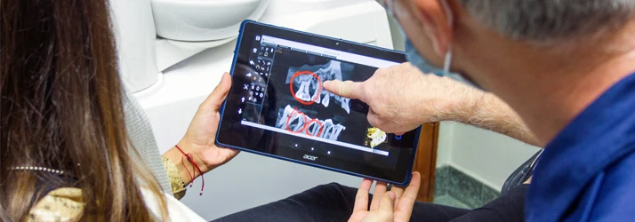 dentist points at an xray to explain to his patient